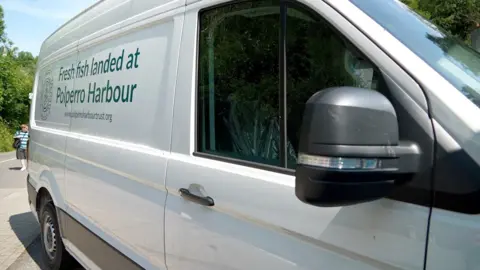 A large white van with the words "Fresh fish landed at Polperro Harbour" and "www.polperroharbourtrust.org"