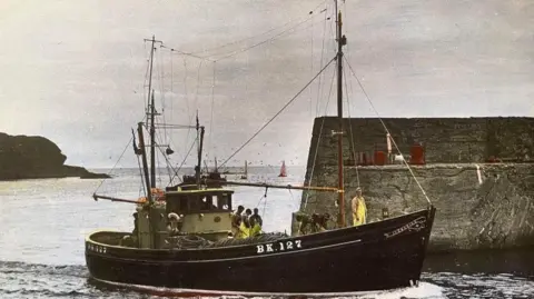 Maritime Heritage Trust An old film image of a old fishing boat with a black hull and a green cabin. There are a number of fishermen on board wearing yellow overalls.