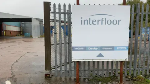 A sign for the Interfloor factory in front a corrugated iron gate