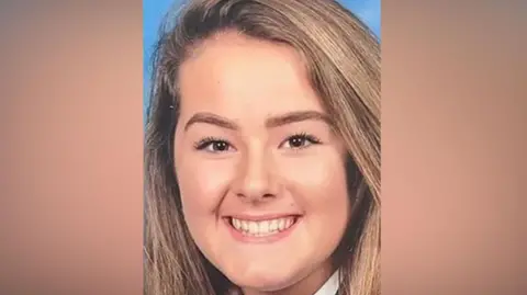 Emily Moore smiles at the camera in a school picture. She has brown eyes and long light brown hair.
