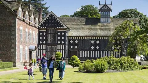 National Trust Images/Chris Lacey A family on the lawn at the Tudor Rufford Old Hall near Ormskirk on a sunny day.                 