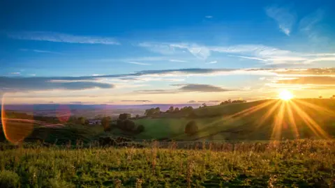 Image of the sun rising over a rural landscape