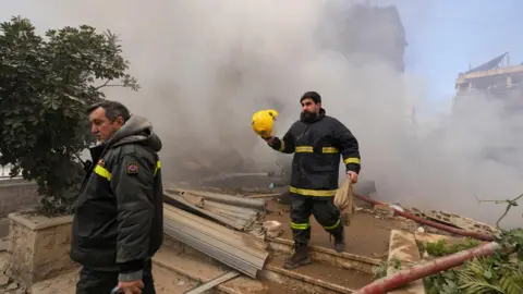 Reuters First responders walk past smoke rising from the site of an Israeli strike in Beirut's southern suburbs, Lebanon (3 March 2026)