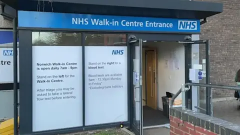 The entrance to Norwich's NHS walk-in centre. There is an automatic door and a large window to the left.
