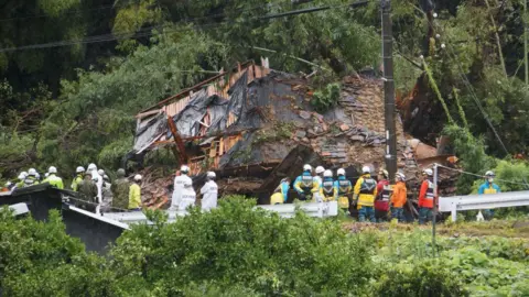 Getty Images Rescue workers outside a house hit by a landslide in Gamagori, Aichi prefecture - 28 August