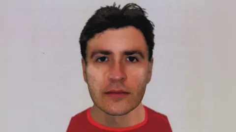 An e-fit of a man wearing a red top. He has black hair, stubble and black eyes.