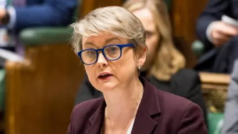 House of Commons Yvette Cooper giving statement from in the House of Commons. Colleagues can be seen sitting in the rows of benches behind her.