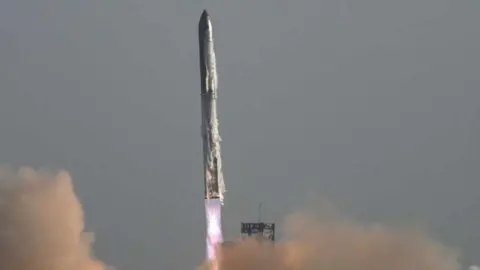 a rocket seen with fire and smoke erupting from below as it lifts off