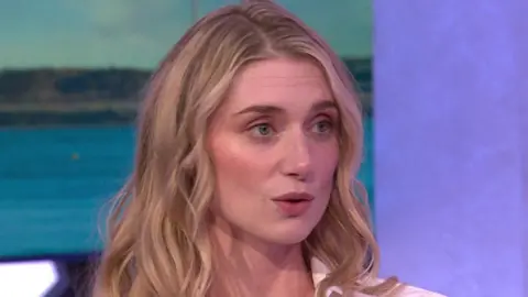 Elizabeth Debicki on the One Show set, she has long, blonde hair and wears a white shirt