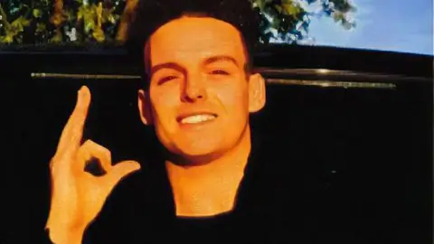 Family handout Stephen Morrisson has black hair and is making a zero and an L sign with his hand.