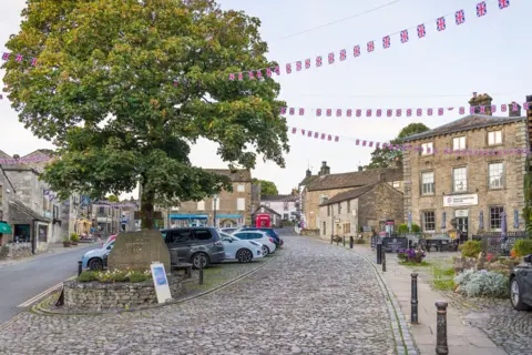 Cobbled streets flanked by stone buildings around a market square