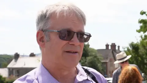 Tamar Toll Action Group chair Scott Slavin. He has short grey hair, is wearing a pink shirt and is wearing dark glasses.
