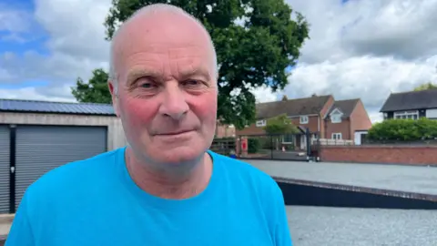 Mr Fowler looks at the camera, with a street scene in the background 