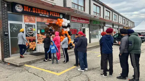 Getty Images Anggota komunitas Sikh berbaris di luar Mr. Singh's Pizza saat pembukaan restoran pizza baru di Mississauga, Ontario, Kanada, pada 5 November 2023.