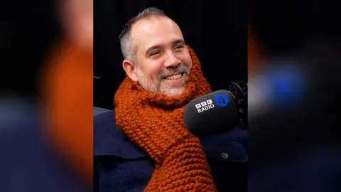 A man wearing a large orange scarf