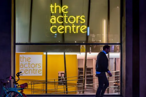 Alamy The Actors Centre in yellow strip lighting with a man walking past the glass window