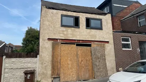 A boarded up two storey building looks run down