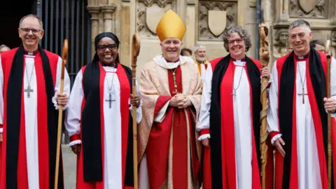 Lambeth Palace Bishop of York Stephen Cottrell is standing in his robes outside Canterbury Cathedral between other bishops in red robes who have been consecrated