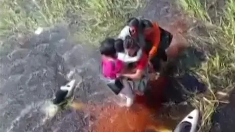 Reuters Survivors stand atop the submerged plane in a swamp in the Amazon