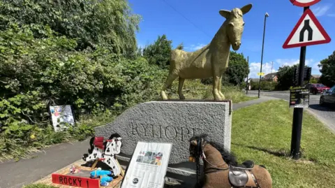 A golden fibre-glass horse sits on top of a grey stone plinth bearing the words 'Ryhope'.