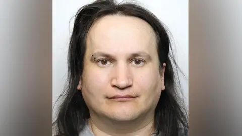 Mugshot Polisi GMP dari Marcin Majerkiewicz, dengan menusuk alis dan rambut hitam panjang