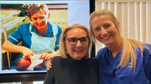 Swansea Bay Health Board Katie Wintle, on the right, with colleague Sharon Cooling. Behind them is a screen showing an image of Ms Cooling holding Ms Wintle as a newborn baby