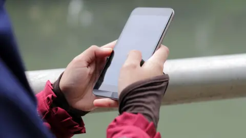 Muslim Girl wearing religious dress and hijab using mobile phone at public park outdoor