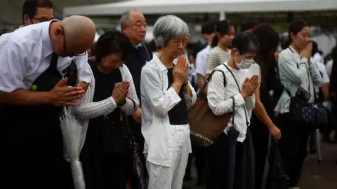 Reuters Attendees pray for the victims on the day of a ceremony commemorating the 80th anniversary of the bombing of Nagasaki, Japan, 9 August 2025