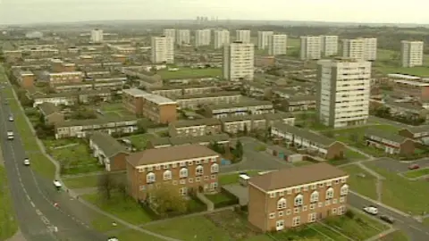 An old aerial image showing a housing estate with many white-coloured tower blocks.