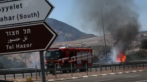 epa رجال الإطفاء منتشرون لإخماد الحريق الذي نشب نتيجة القذائف التي أُطلقت من جنوب لبنان، في أيلت هشار، الجليل الأعلى، شمال إسرائيل.