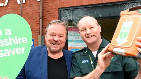 Robbins with a paramedic holding a defibrillator