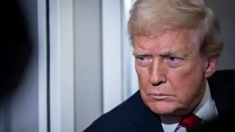 A close photo of Trump, who is wearing a dark suit and red tie