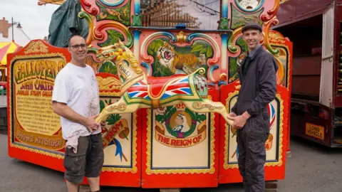 Black Country Living Museum Two men holding a wooden horse from the carrousel ride smiling at the camera