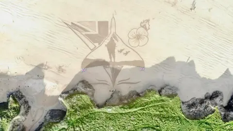 Rocks Up Overhead photo showing sand art of a Vulcan aircraft with a poppy, a soldier and union lags