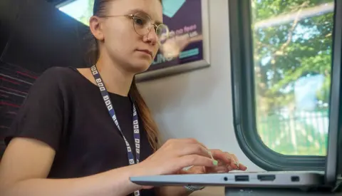 Grace Dean checks wi-fi access on her laptop as she travels on a train to Norwich