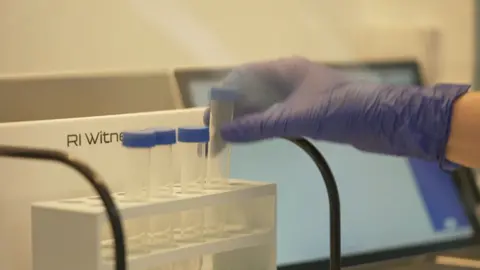 A person placing a test sample into a tray