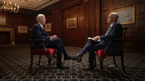 Joe Biden and Nick Robinson sit opposite each other