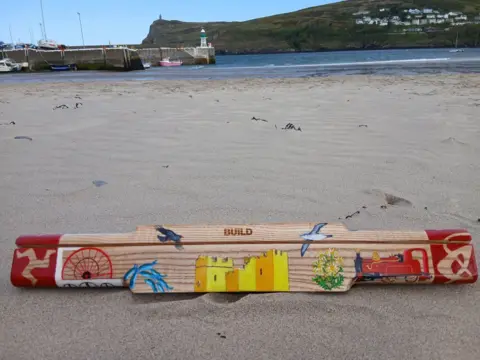 Lesley Sleight The baton sits on a sandy beach. 