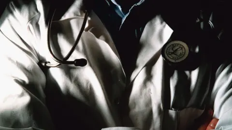 Close up of man's torso, wearing a white lab coat and stethoscope 