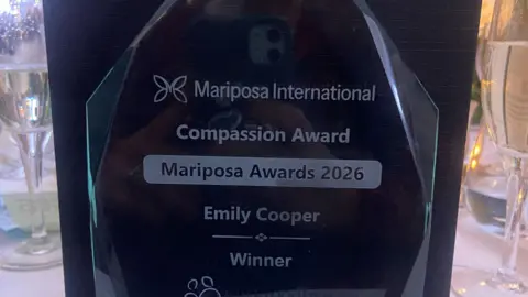 RWT Part of the glass award which has the inscription: "Mariposa International. Compassion Award. Emily Cooper. Winner." 