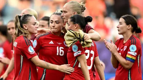 Wales players on the pitch put their arms around each other after their 3-0 defeat by the Netherlands at Euro 2025.