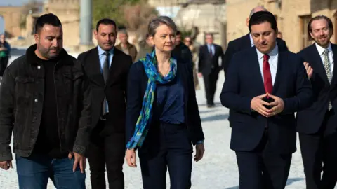 Lee Durant/BBC Yvette Cooper walking in Erbil while flanked by five men.