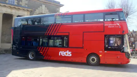Salisbury Reds An electric bus painted in red with the Salisbury Reds logo prominently displayed on the side. 