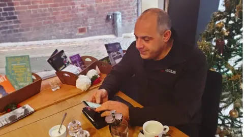 Facebook group moderator Jason Lawal on his phone