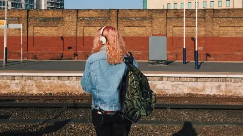 Getty Images A woman waits at a train platform