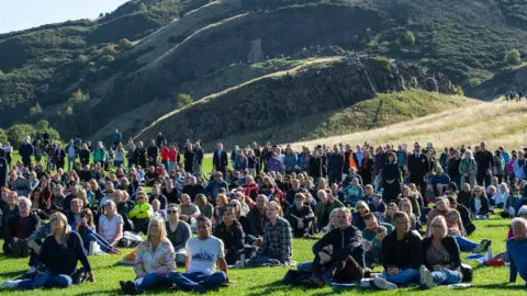 PA Media Members of the public watch the State Funeral of Queen Elizabeth II on a big screen in Holyrood Park, Edinburgh