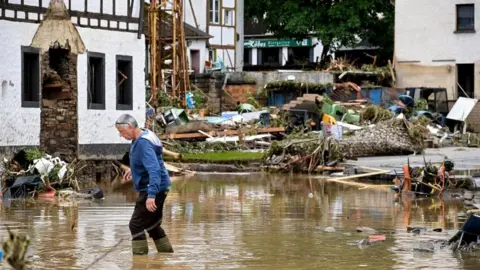 EPA A man walks through floodwaters in Schuld, Germany