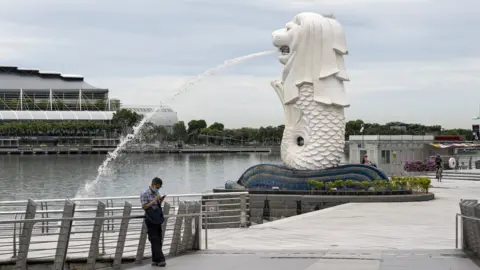 Getty Images A lone man by the Merlion statue in Singapore