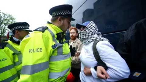 PA Media A police officer speaking to a protester next to the coach