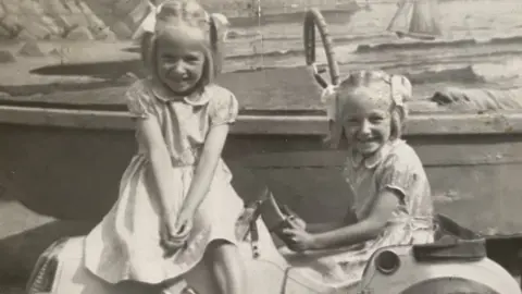 Wright Family Two girls playing on a toy car